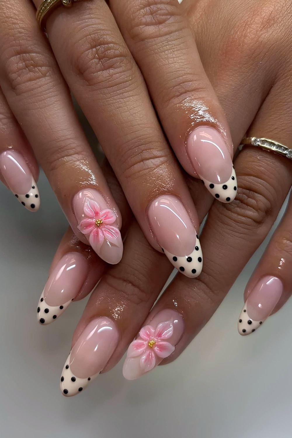 Beige and black polka dot nails with pink 3d flower accents