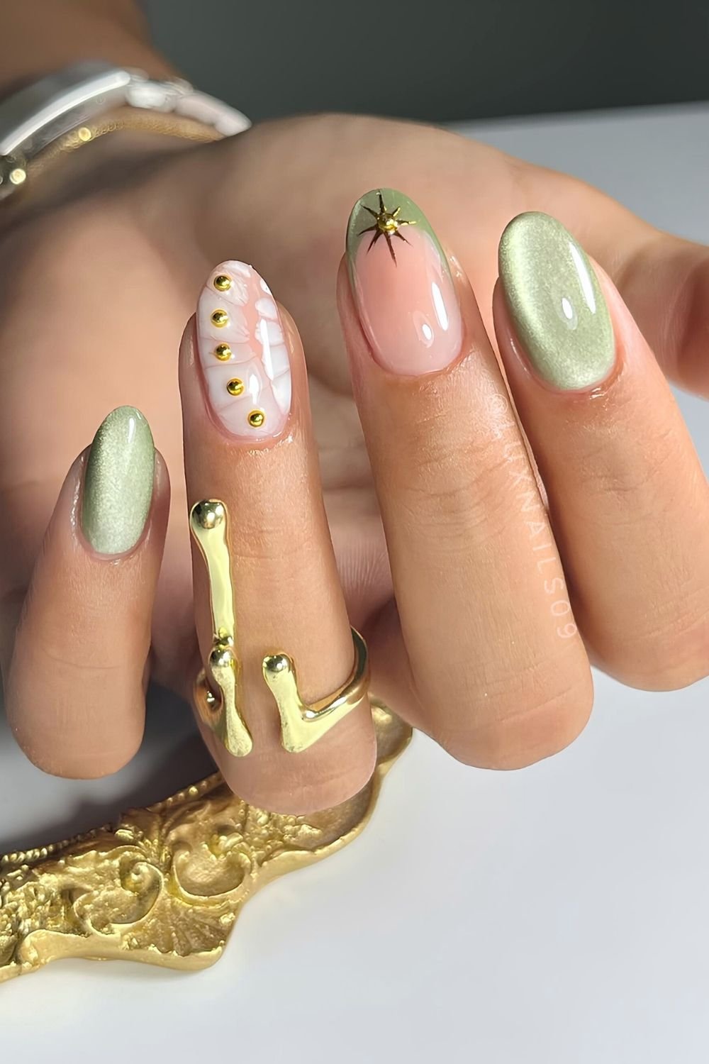 Light green cat eye nails with white croc pattern and gold chrome accents