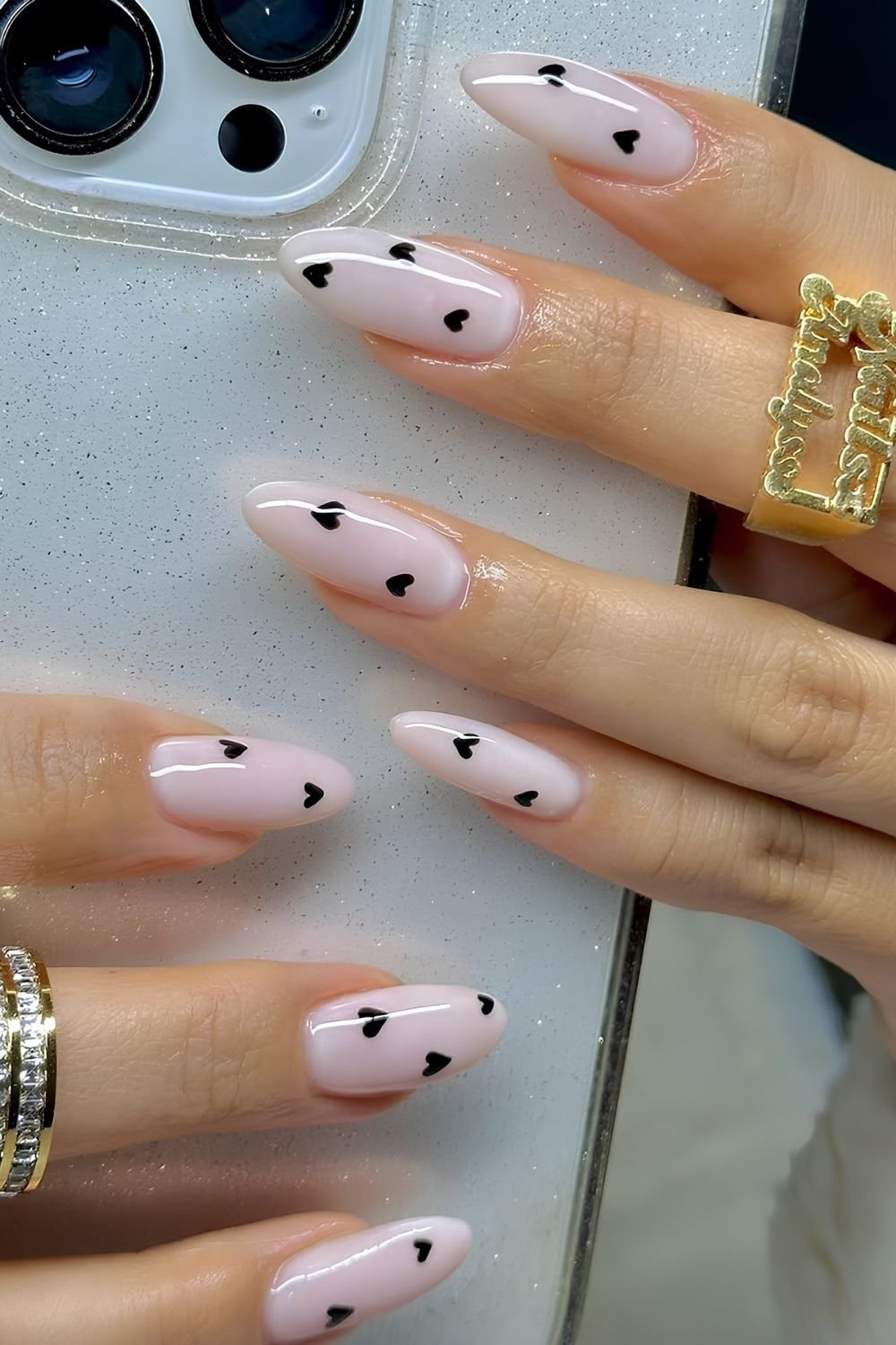 Milky pink almond nails with tiny black heart accents