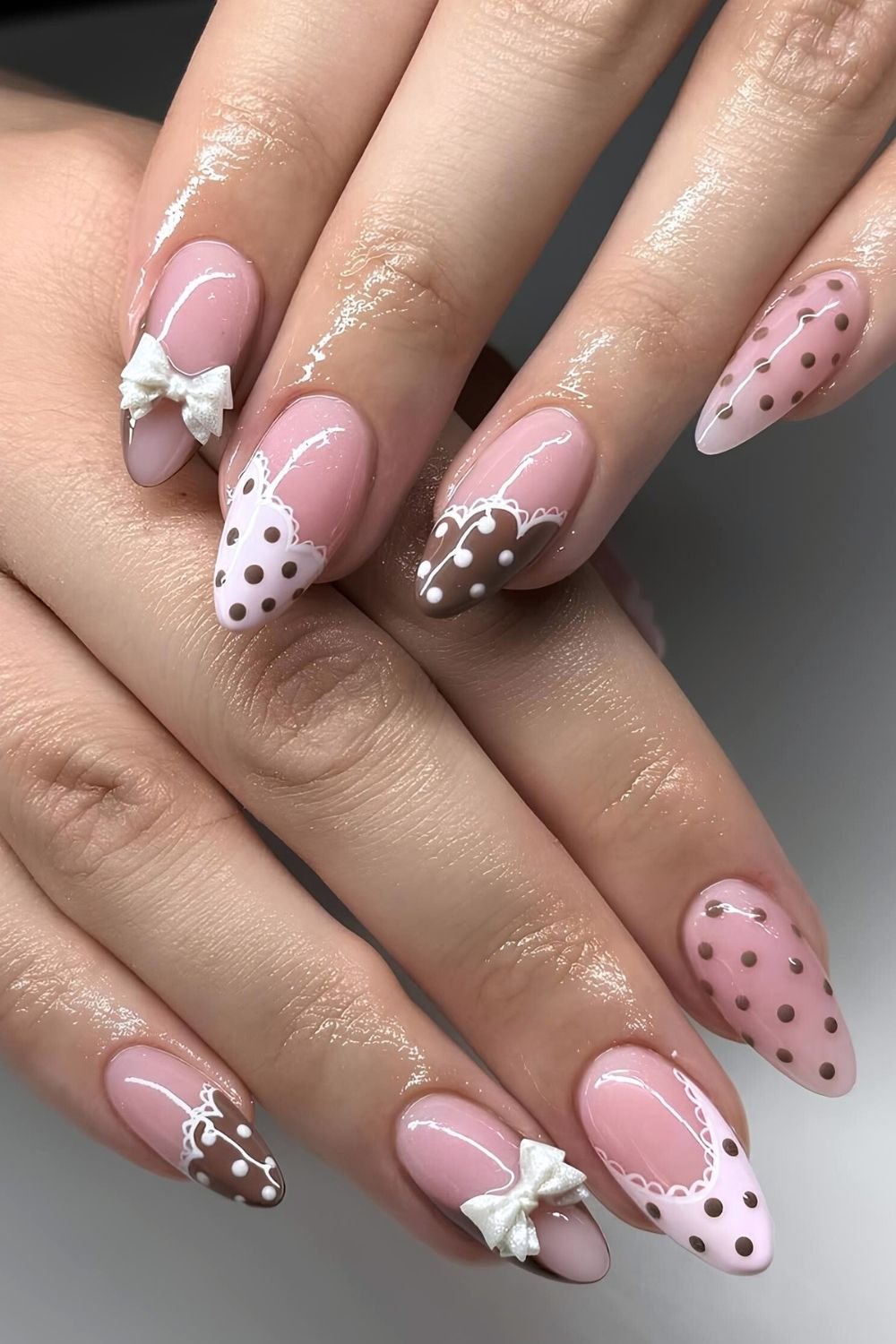 Pink and brown polka dot nails with lace outlines and 3d bows