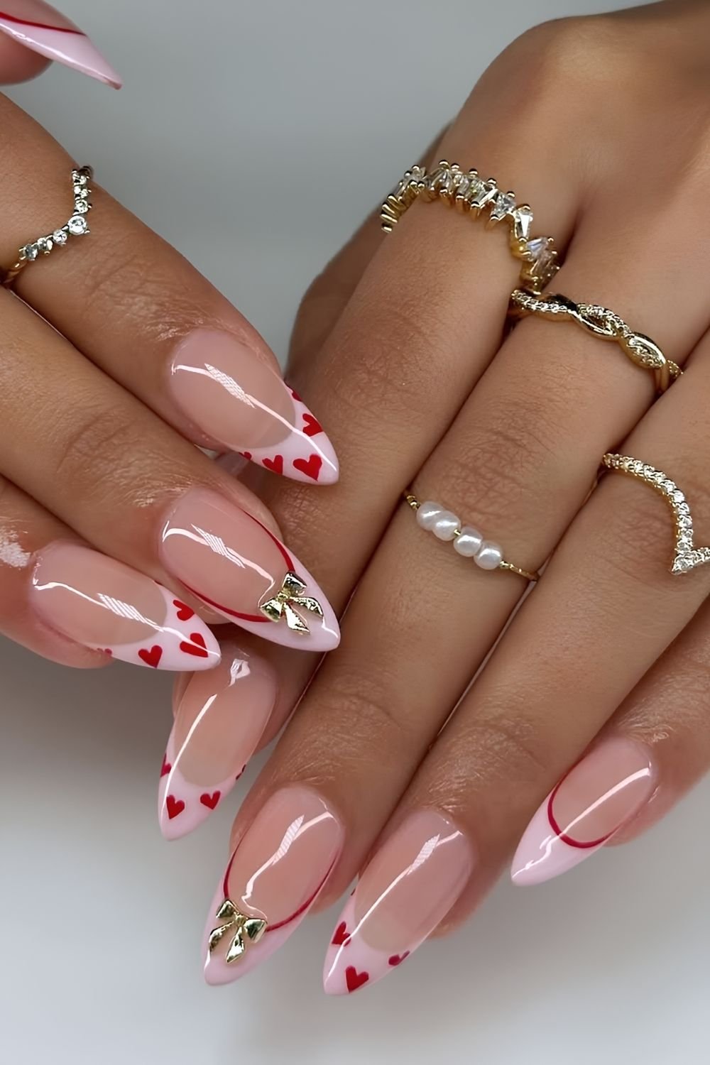 Pink french tips with red hearts, outlines and bow accents