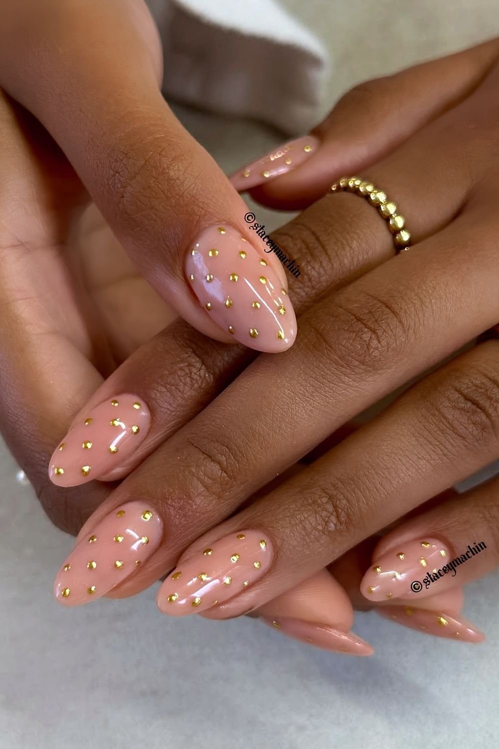 Soft peach nails with golden chrome polka dots