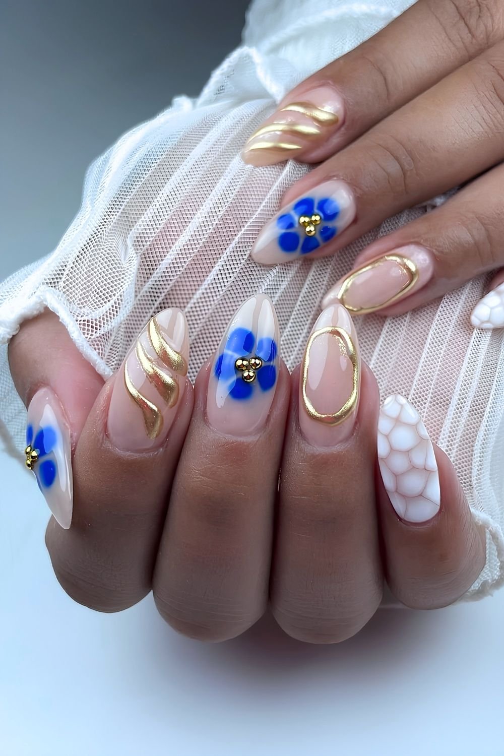 Blue blooming gel floral nails with golden chrome accents