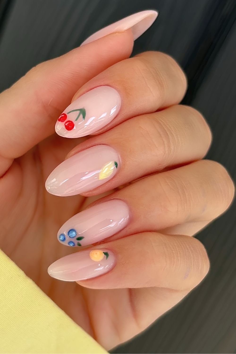 Fruit salad nails featuring milky pink base with fruit nail art