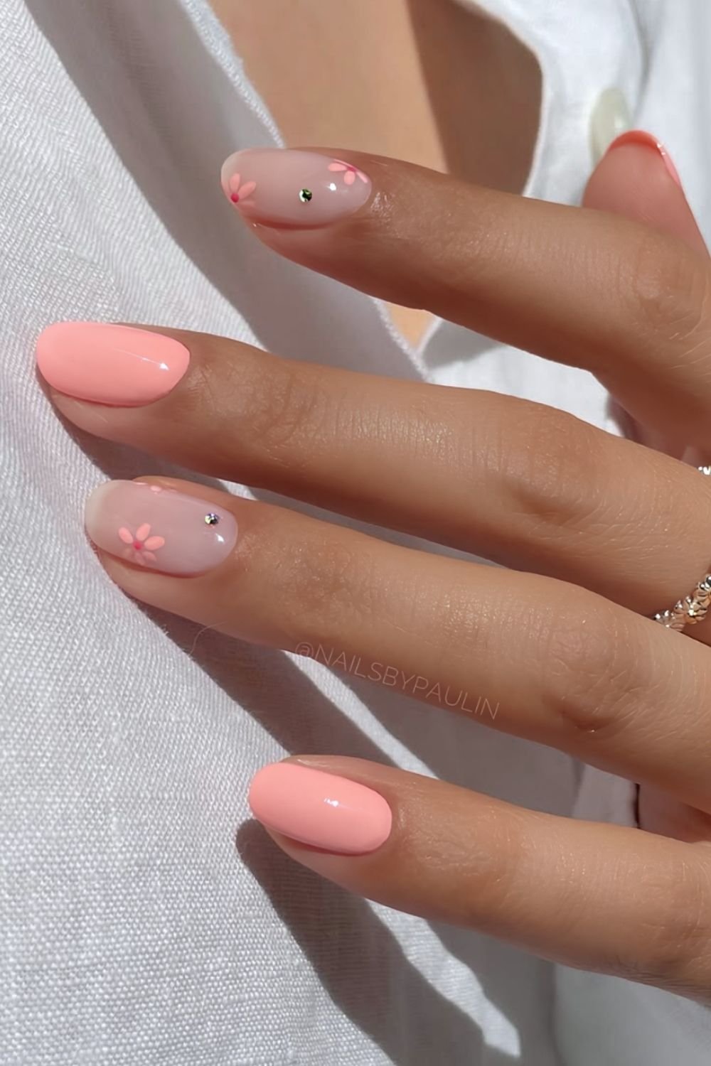 Peach and milky white nails with floral and rhinestone accents