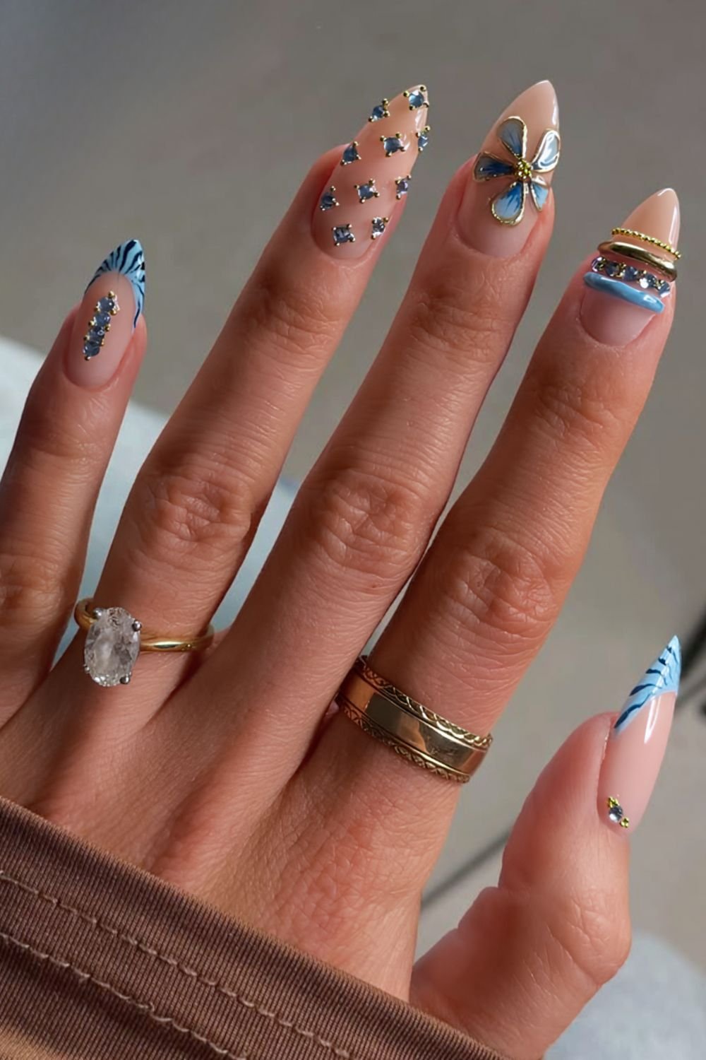 Blue floral nails with nail rings, gems and chrome outlined flower