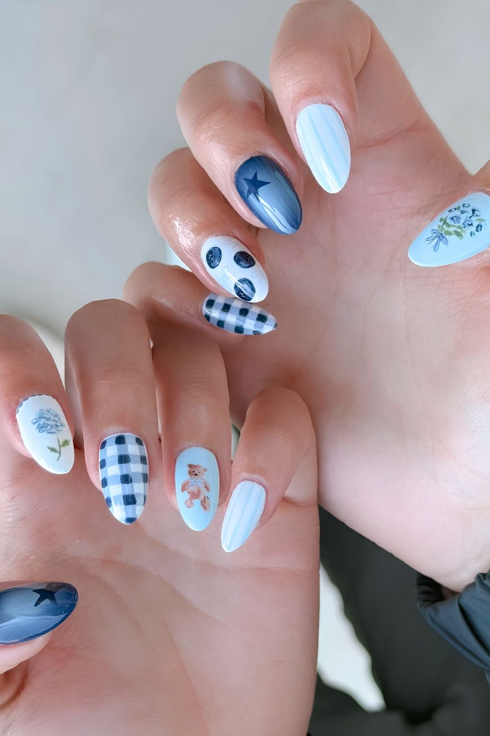 Light and dark blue nails with gingham, floral, blueberry, star and teddy bear accents