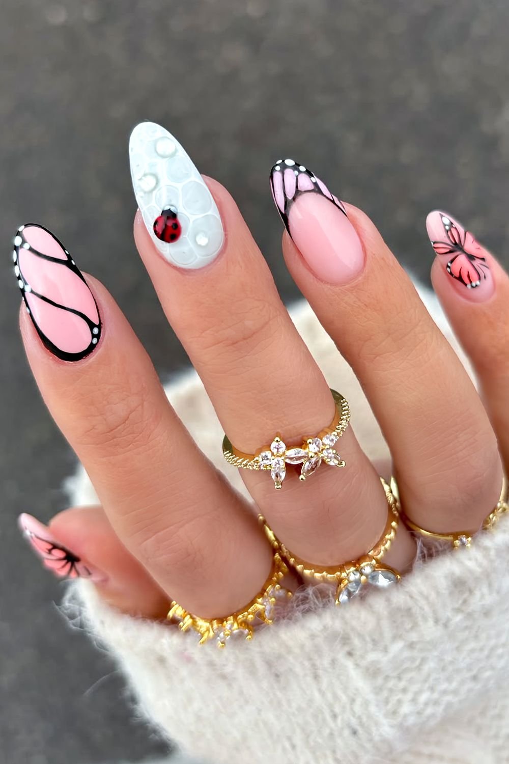 Peach butterfly nails with blue dew-drop accent nail with a ladybug