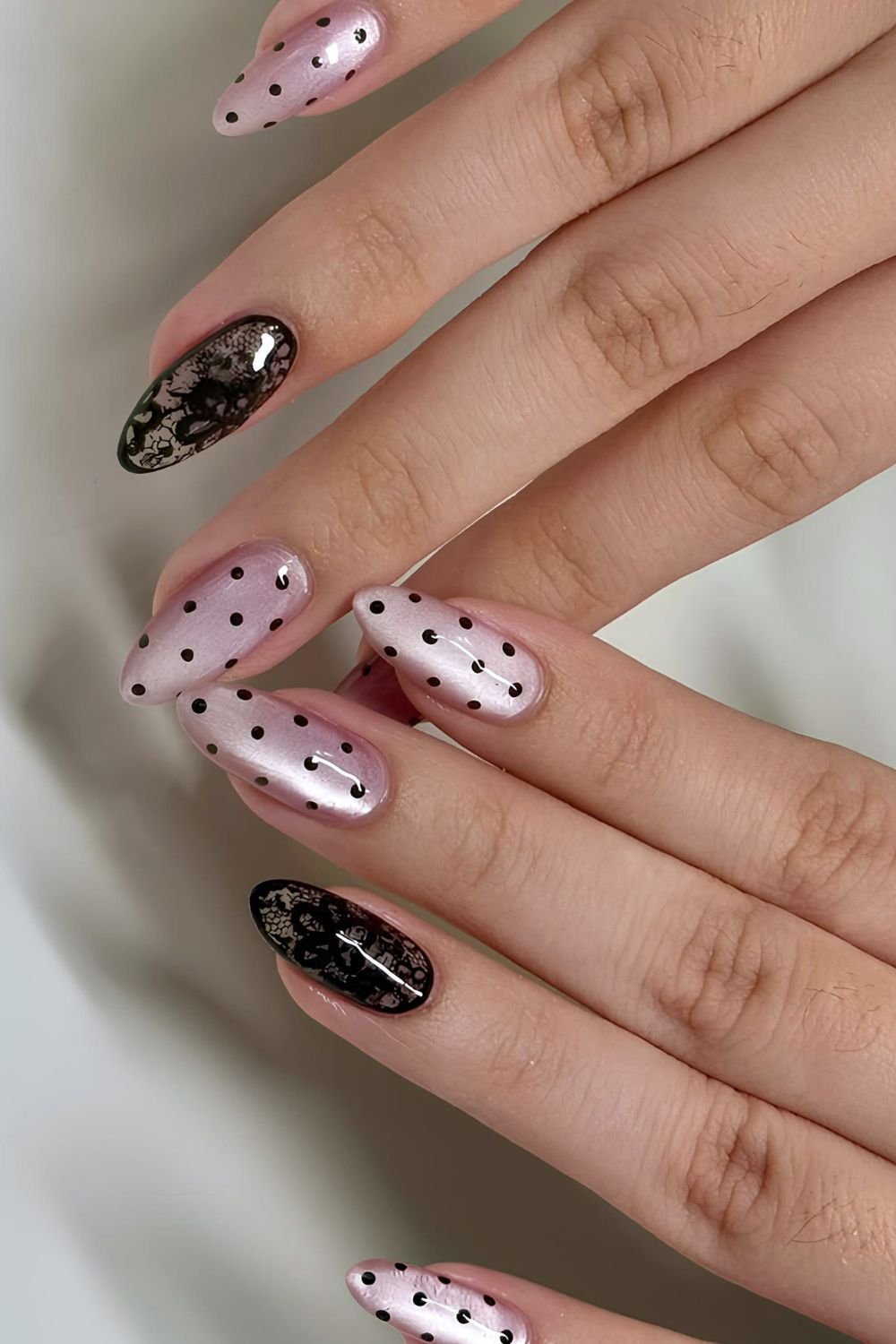 Pink cat eye nails with black dots and black lace design