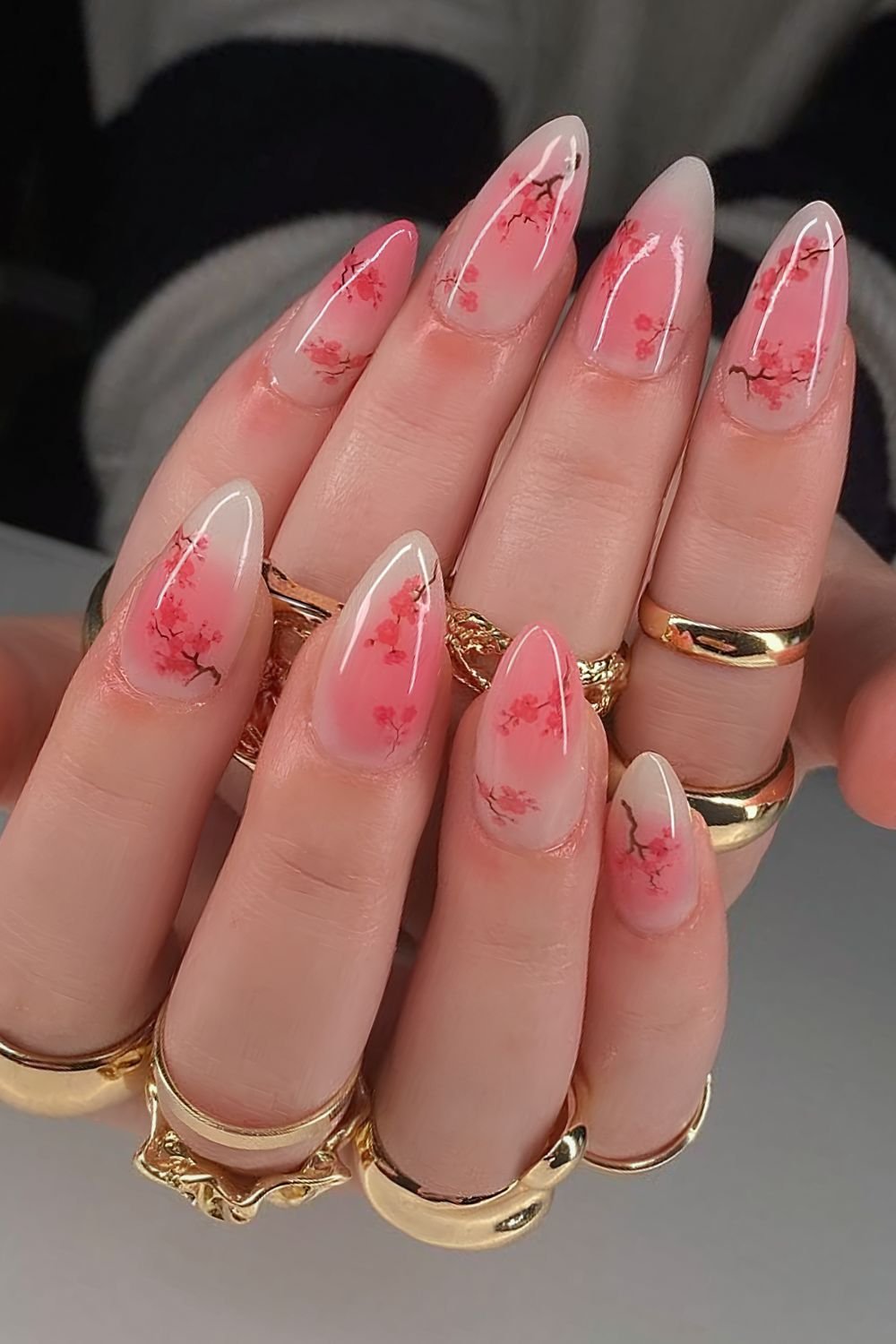 Reddish-pink aura nails with red cherry blossom branch design