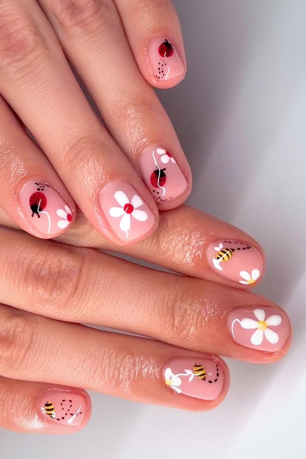 Short neutral nails with daisy ladybug and bee accents