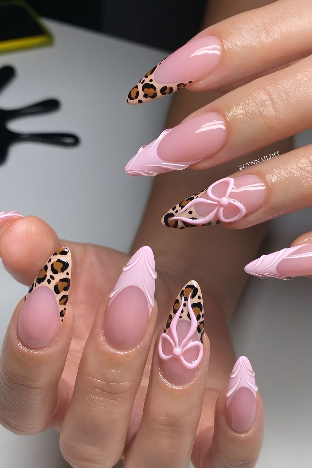 Light pink and leopard print French nails with 3D bow accents