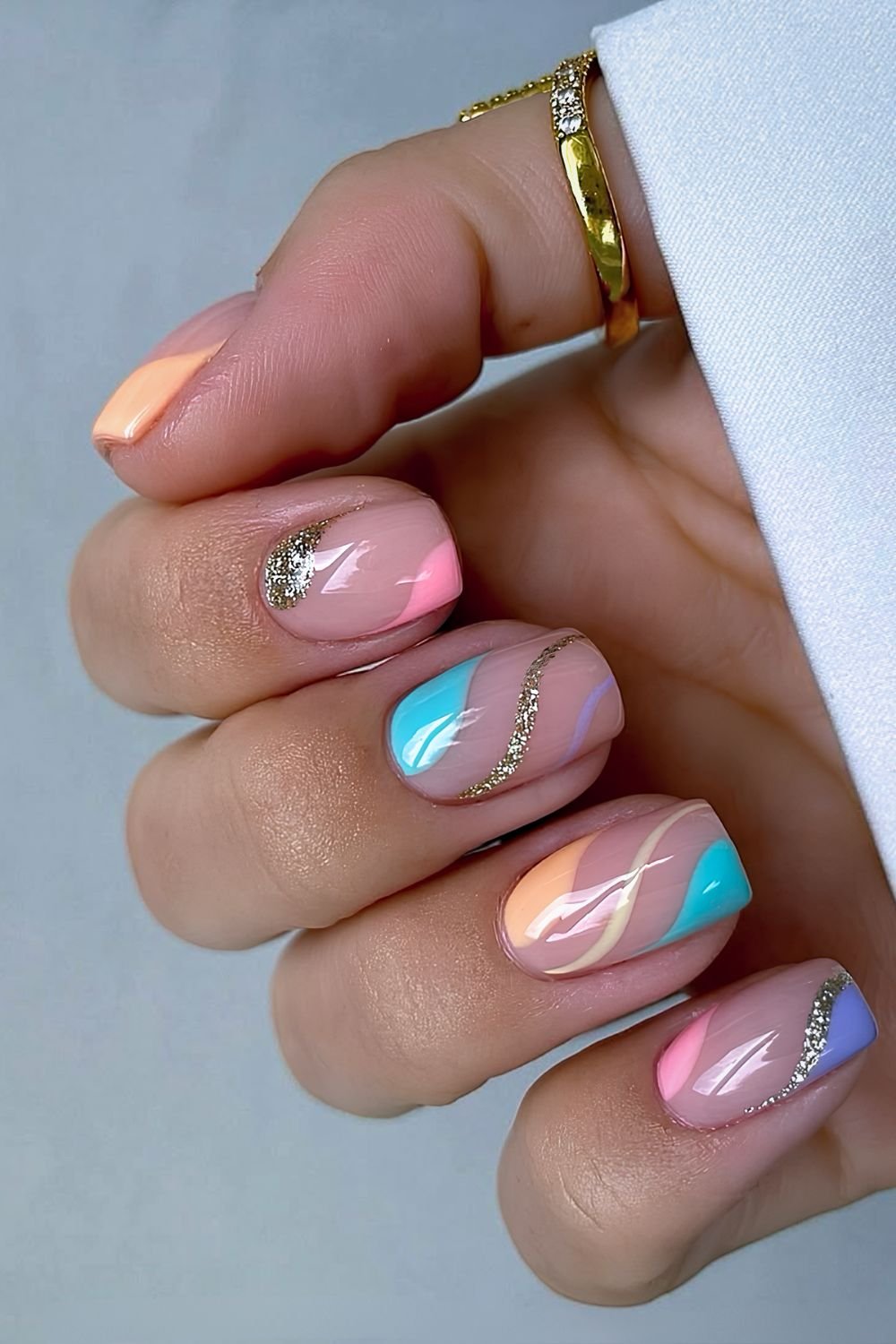 Negative space multicolored pastel nails with gold glitter accents