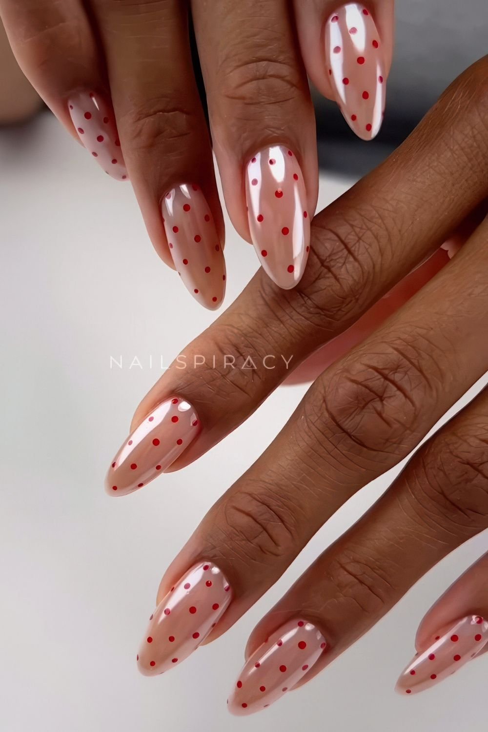 Glazed neutral pink nails with red polka dots